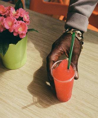 A hand holding a red slush drink with a green straw in it